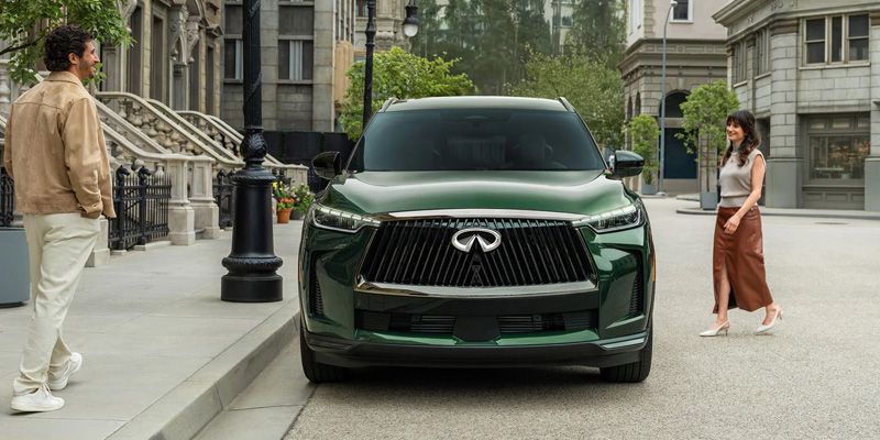 A green Infiniti SUV parked on a city street